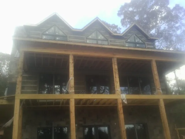 Dormers and porch framing on a large log home under construction — Roof Coating work by our crew in Stockport