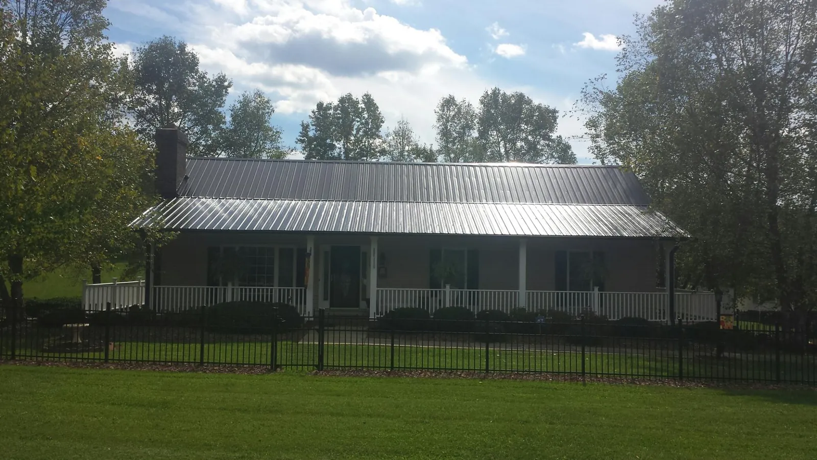 Gray metal roof on a brick ranch with a full width front porch — Gutter Guard Installation work by our crew in Stockport