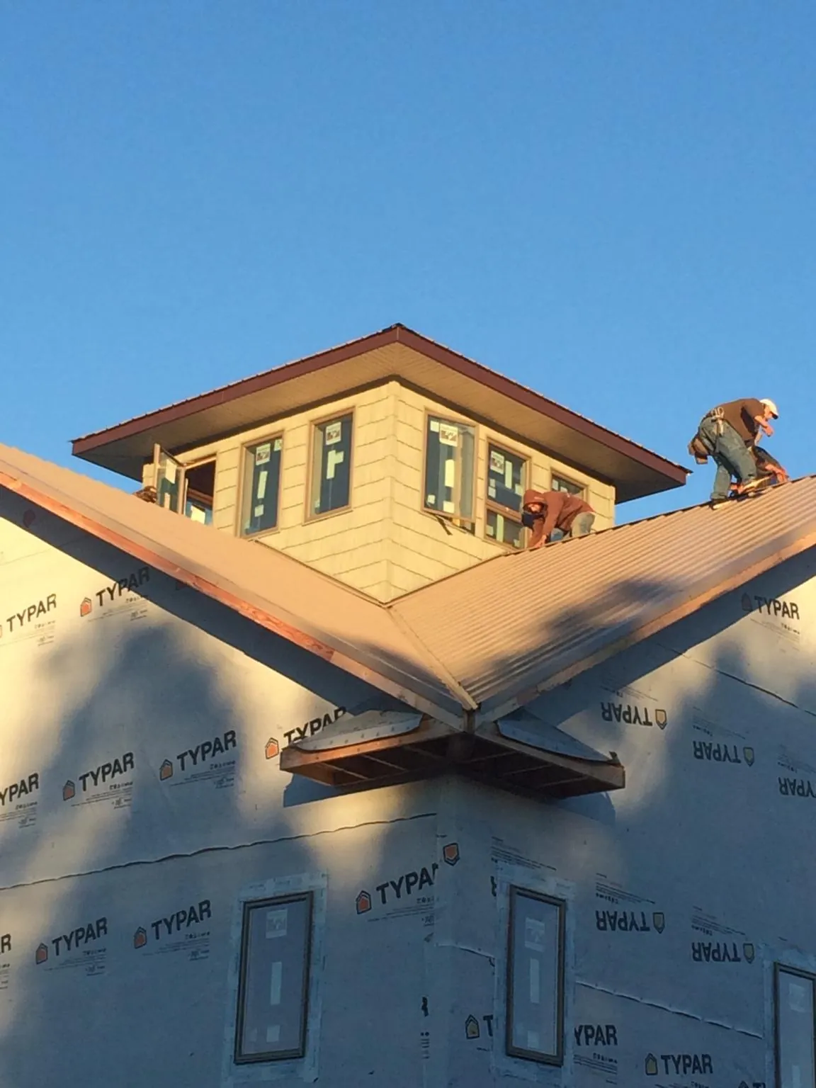 Roofers working around a rooftop cupola on a new metal roof at sunset — Roof Waterproofing in Stockport by Roofing Brothers
